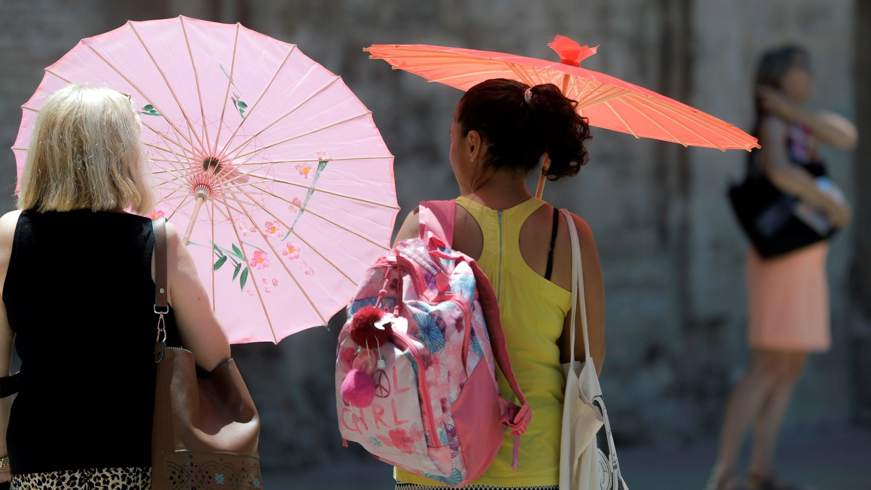 Dos mujeres se protegen del calor con unas sombrillas