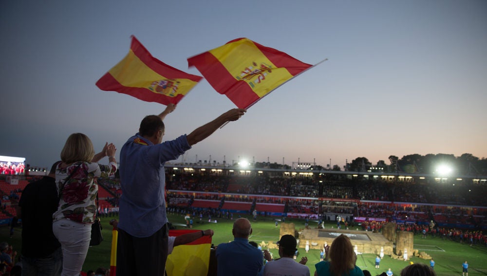 Dos personas agitan banderas al paso de los atletas españoles durante la inauguración de los XVIII Juegos Mediterráneos