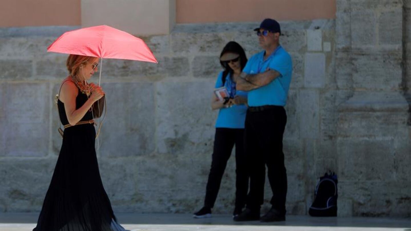 Una mujer se protege del calor con un paraguas