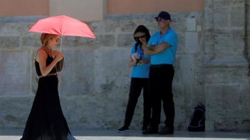 Una mujer se protege del calor con un paraguas