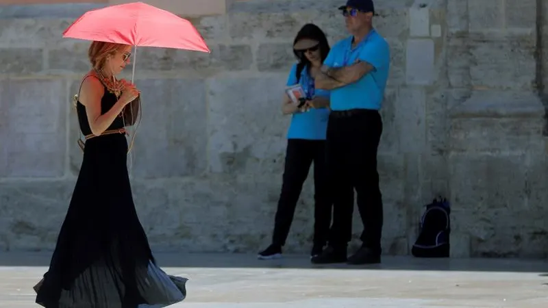 Una mujer se protege del calor con un paraguas