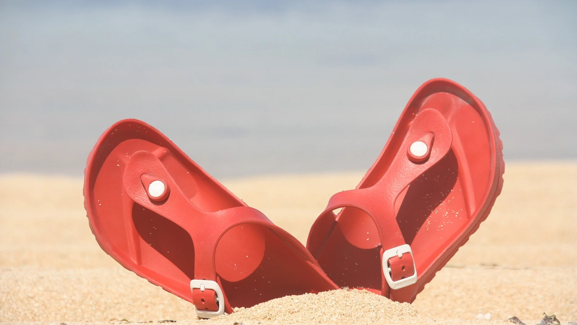Imagen de unas chanclas en la arena de la playa