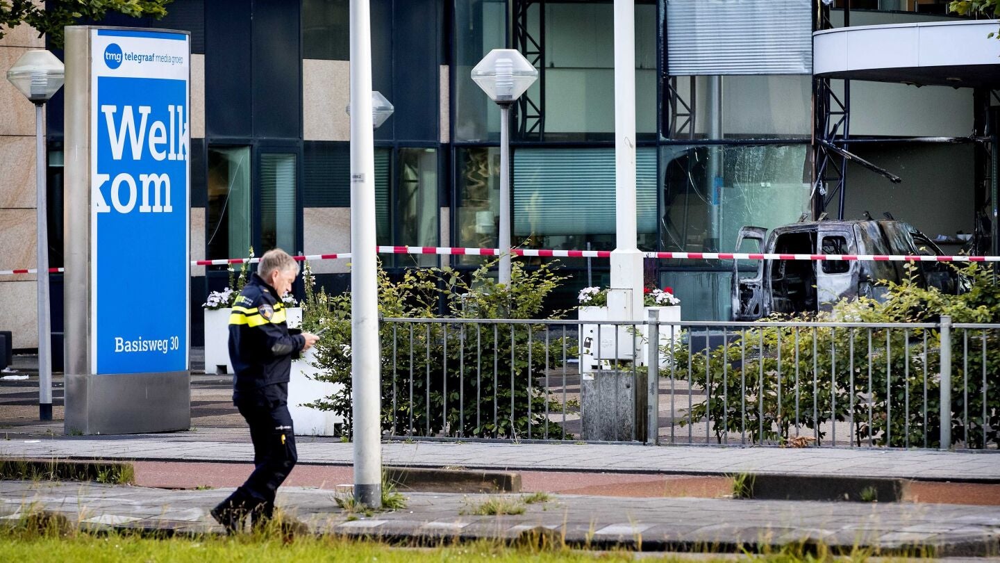 Un oficial de la polic&iacute;a pasa delante de la furgoneta que se empotr&oacute; contra la sede del diario 'De Telegraaf' en &Aacute;msterdam