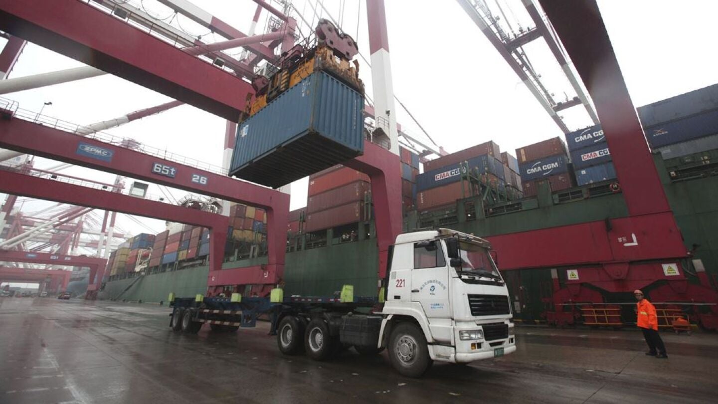 Un operario observa las labores de carga de un contenedor en un cami&oacute;n en el puerto de Qingdao