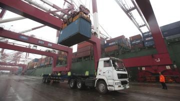 Un operario observa las labores de carga de un contenedor en un camión en el puerto de Qingdao