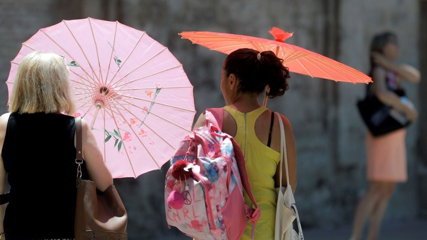 Imagen de archivo de dos mujeres protegi&eacute;ndose del calor con unas sombrillas