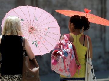 Imagen de archivo de dos mujeres protegiéndose del calor con unas sombrillas Imagen de archivo de dos mujeres protegiéndose del calor con unas sombrillas