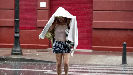 Una mujer camina bajo la lluvia durante una tormenta Una mujer camina bajo la lluvia durante una tormenta