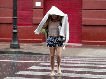 Una mujer camina bajo la lluvia durante una tormenta Una mujer camina bajo la lluvia durante una tormenta