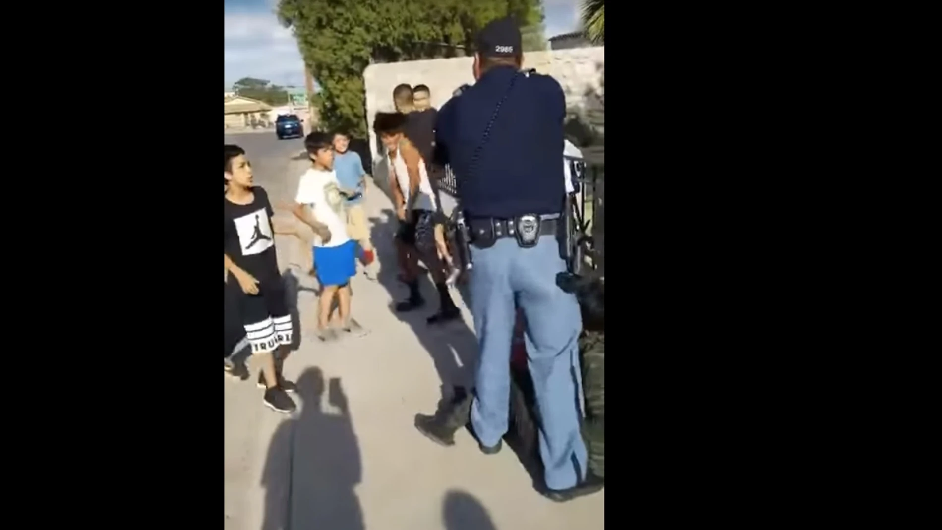 Un policía amenaza con su pistola a unos niños