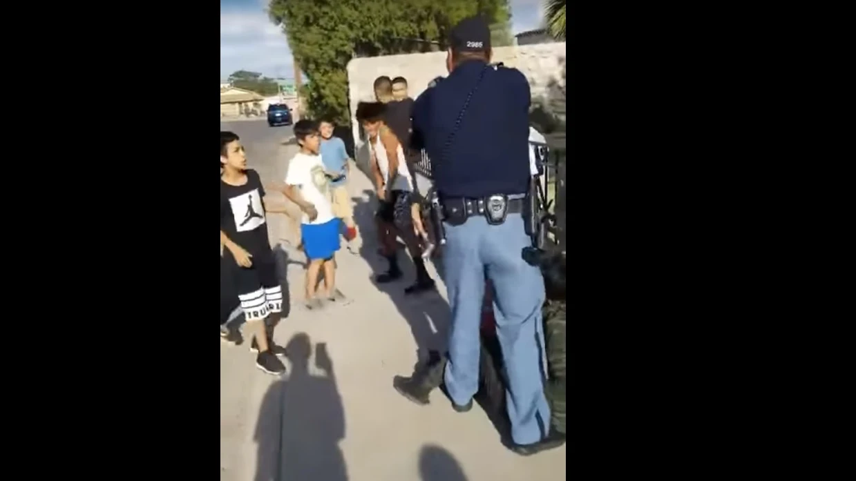 Un policía amenaza con su pistola a unos niños