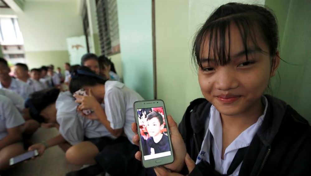 Una estudiante tailandesa muestra una fotografía de su compañero de clase
