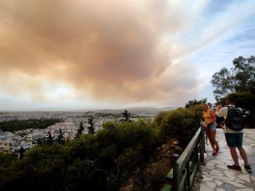 Unos turistas fotografían las nubes densas de humo que se expanden en el cielo debido un incendio en las montañas de Gerania, a 54 km de Atenas Unos turistas fotografían las nubes densas de humo que se expanden en el cielo debido un incendio en las montañas de Gerania, a 54 km de Atenas