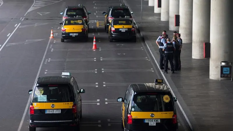 Un grupo de taxistas permanecen parados con sus vehículos en el Aeropuerto de Barcelona