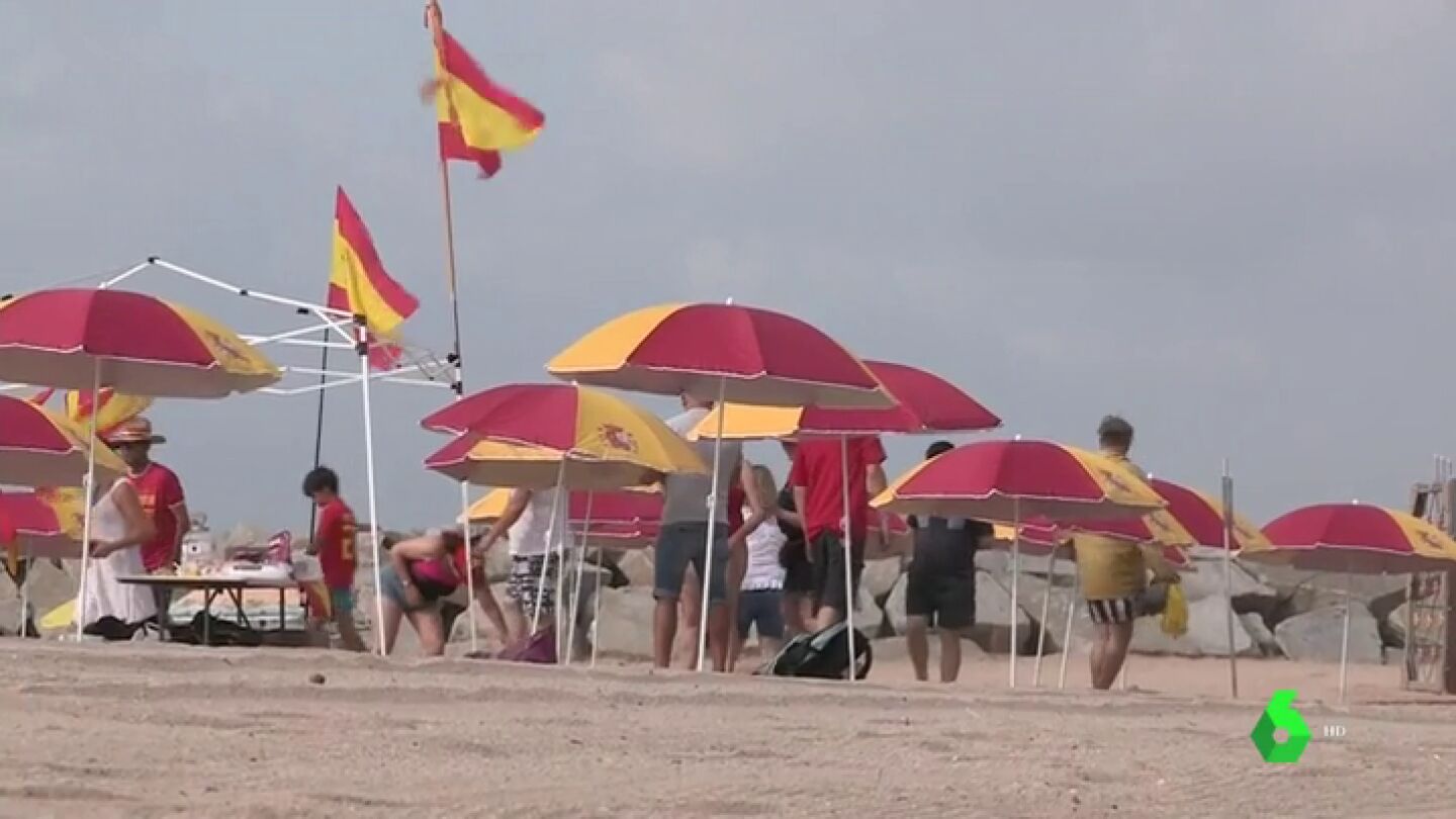 Unas 30 personas han llenado esta playa de Montgat, Barcelona, con sombrillas con la bandera de Espa&ntilde;a