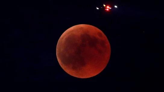 Imagen de un avión que pasa sobre la Luna durante el eclipse lunar más largo del siglo XXI Imagen de un avión que pasa sobre la Luna durante el eclipse lunar más largo del siglo XXI