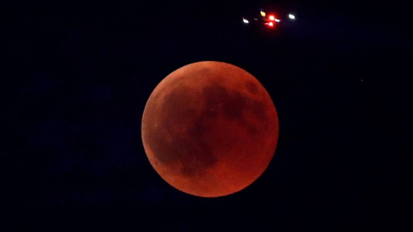 Imagen de un avión que pasa sobre la Luna durante el eclipse lunar más largo del siglo XXI Imagen de un avión que pasa sobre la Luna durante el eclipse lunar más largo del siglo XXI