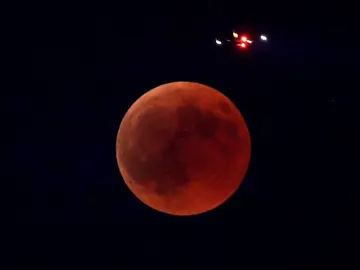 Imagen de un avión que pasa sobre la Luna durante el eclipse lunar más largo del siglo XXI Imagen de un avión que pasa sobre la Luna durante el eclipse lunar más largo del siglo XXI