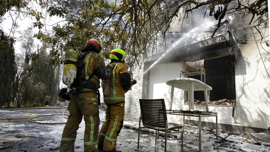 Dos bomberos refrescan el interior de una de las viviendas afectadas por el incendio forestal de Llutxent Dos bomberos refrescan el interior de una de las viviendas afectadas por el incendio forestal de Llutxent