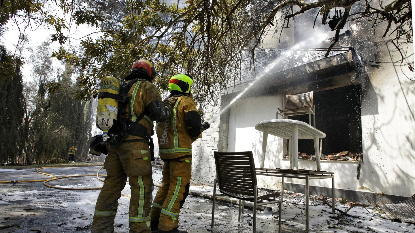Dos bomberos refrescan el interior de una de las viviendas afectadas por el incendio forestal de Llutxent Dos bomberos refrescan el interior de una de las viviendas afectadas por el incendio forestal de Llutxent