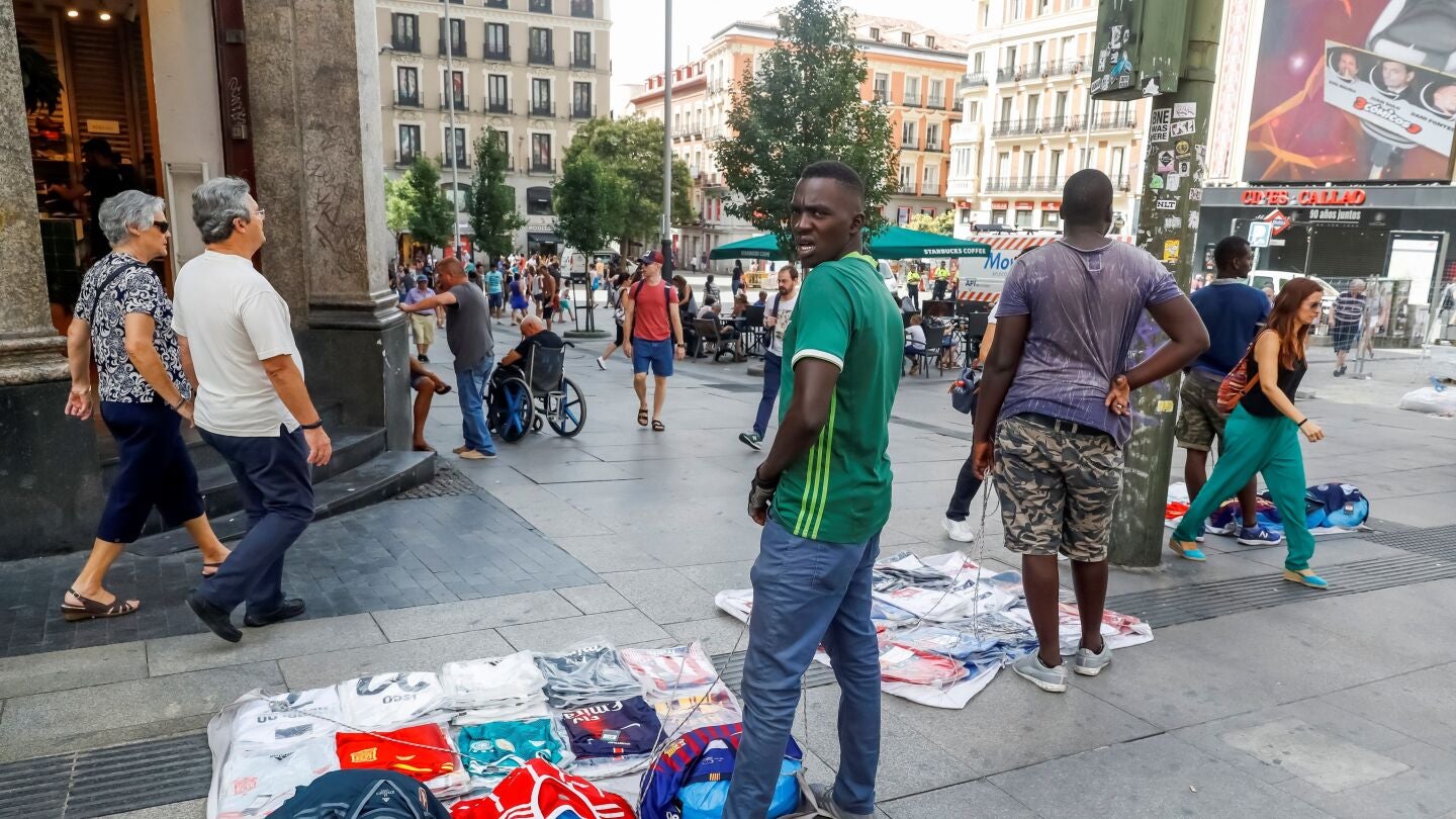 Un grupo de manteros muestra sus productos al p&uacute;blico que transita por la Gran V&iacute;a de Madrid