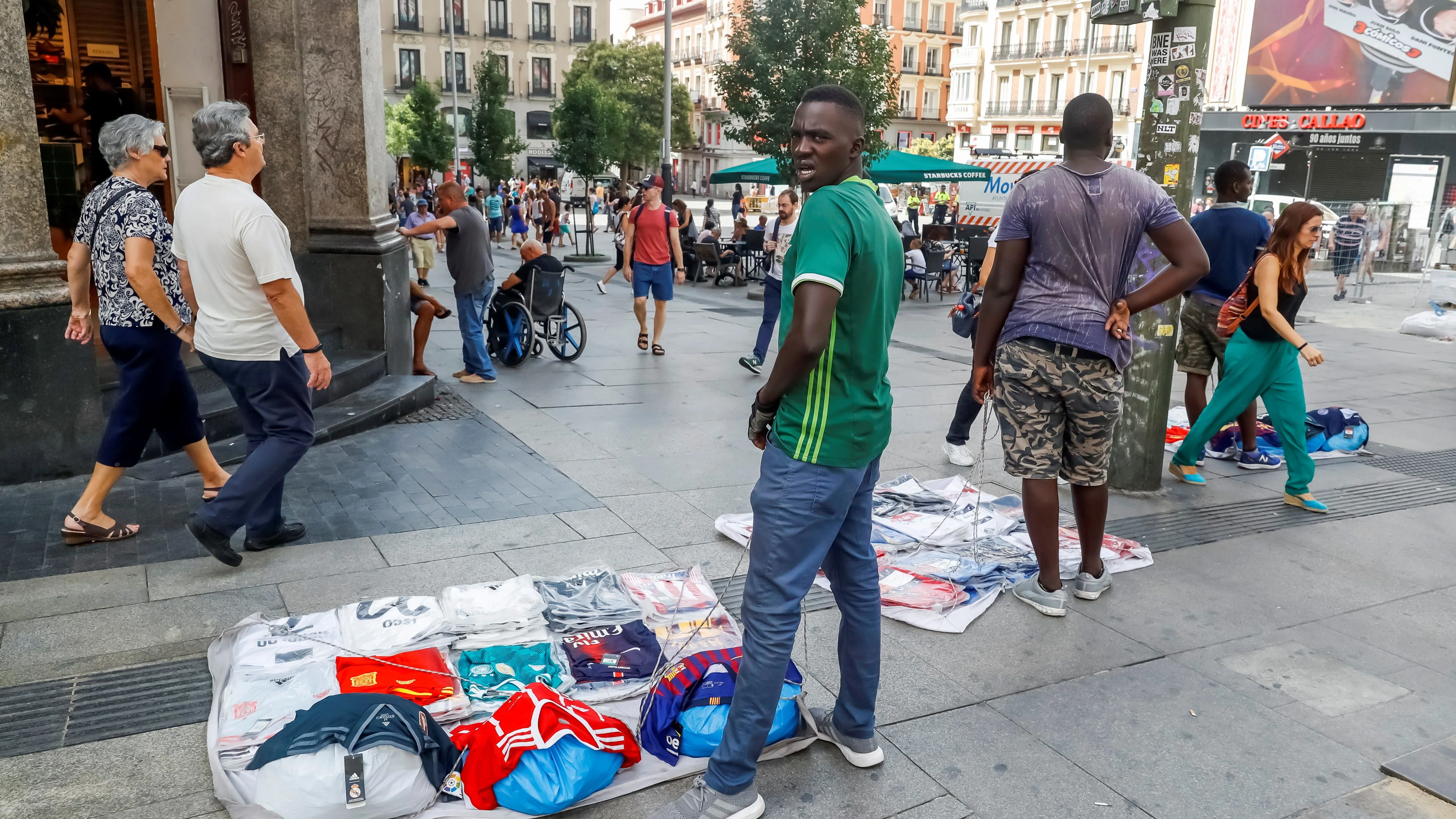 Un grupo de manteros muestra sus productos al público que transita por la Gran Vía de Madrid