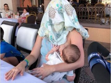Mujer cubierta mientras amamanta a su hijo Mujer cubierta mientras amamanta a su hijo