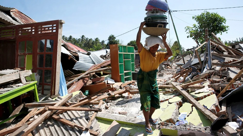 Una mujer carga con sus pertenencias entre los escombros en Lombok 