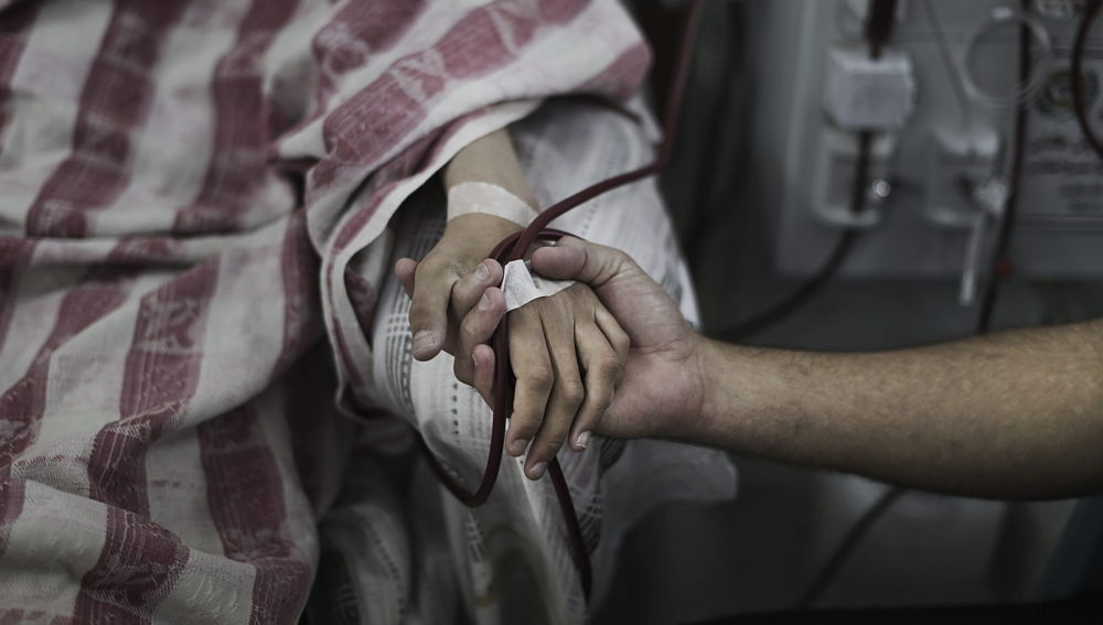 Un paciente palestino es consolado mientras recibe tratamiento en el área de diálisis del hospital al-Shifa, en Gaza