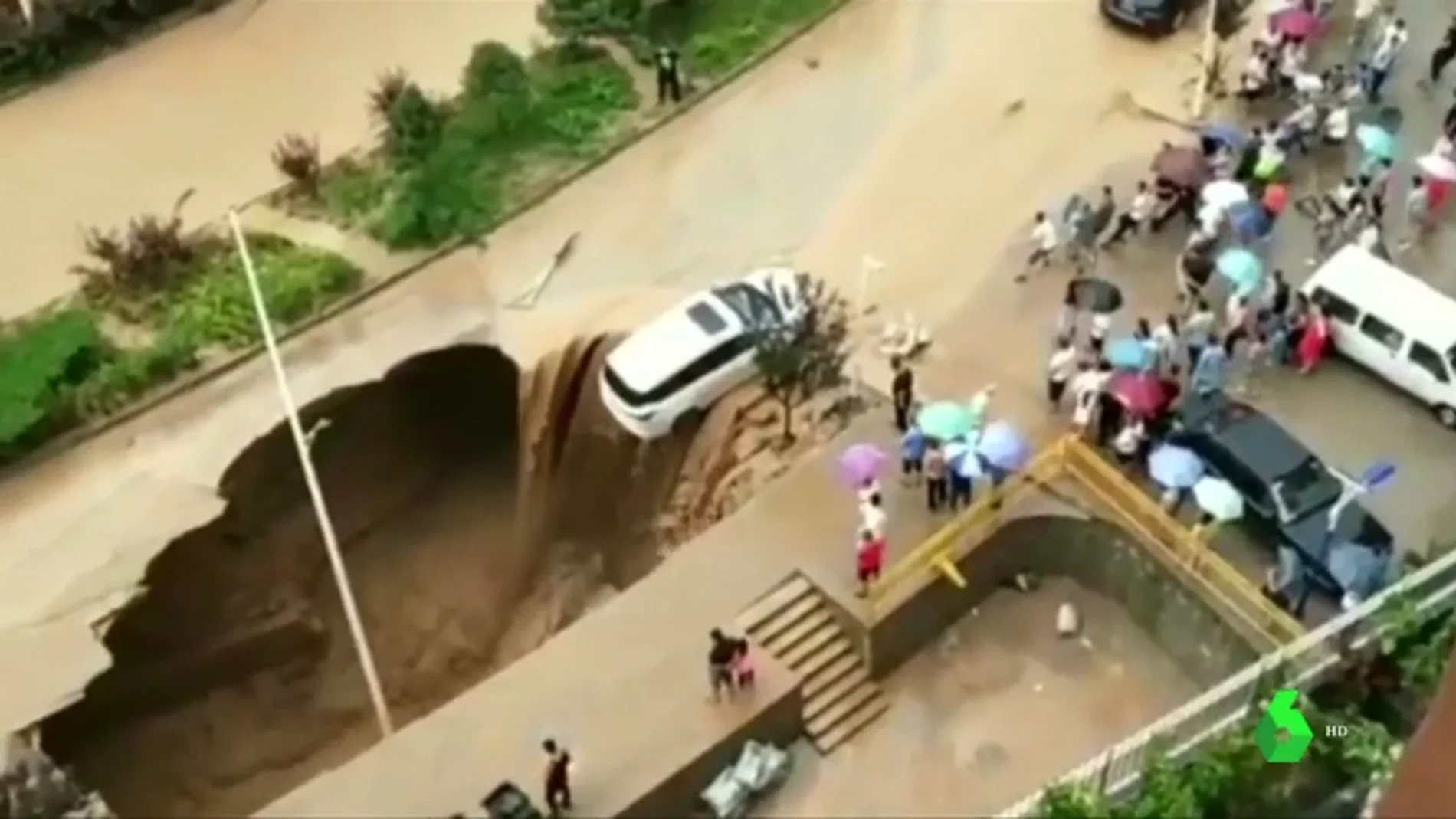 Un coche, a punto de caer a un socavón en China provocado por las fuertes lluvias