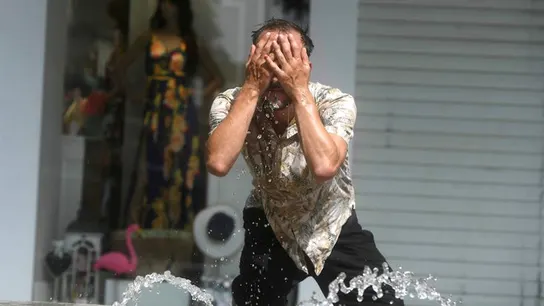 Un hombre intenta refrescarse en una fuente Un hombre intenta refrescarse en una fuente