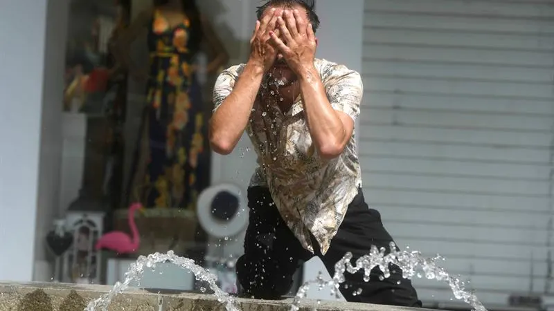 Un hombre intenta refrescarse en una fuente 