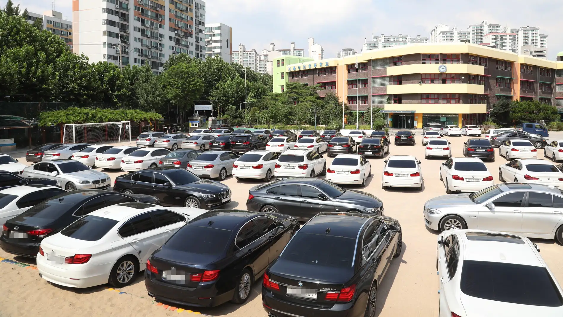 Vista de decenas de vehículos BMW permanecen aparcados en el patio de un colegio en Seúl