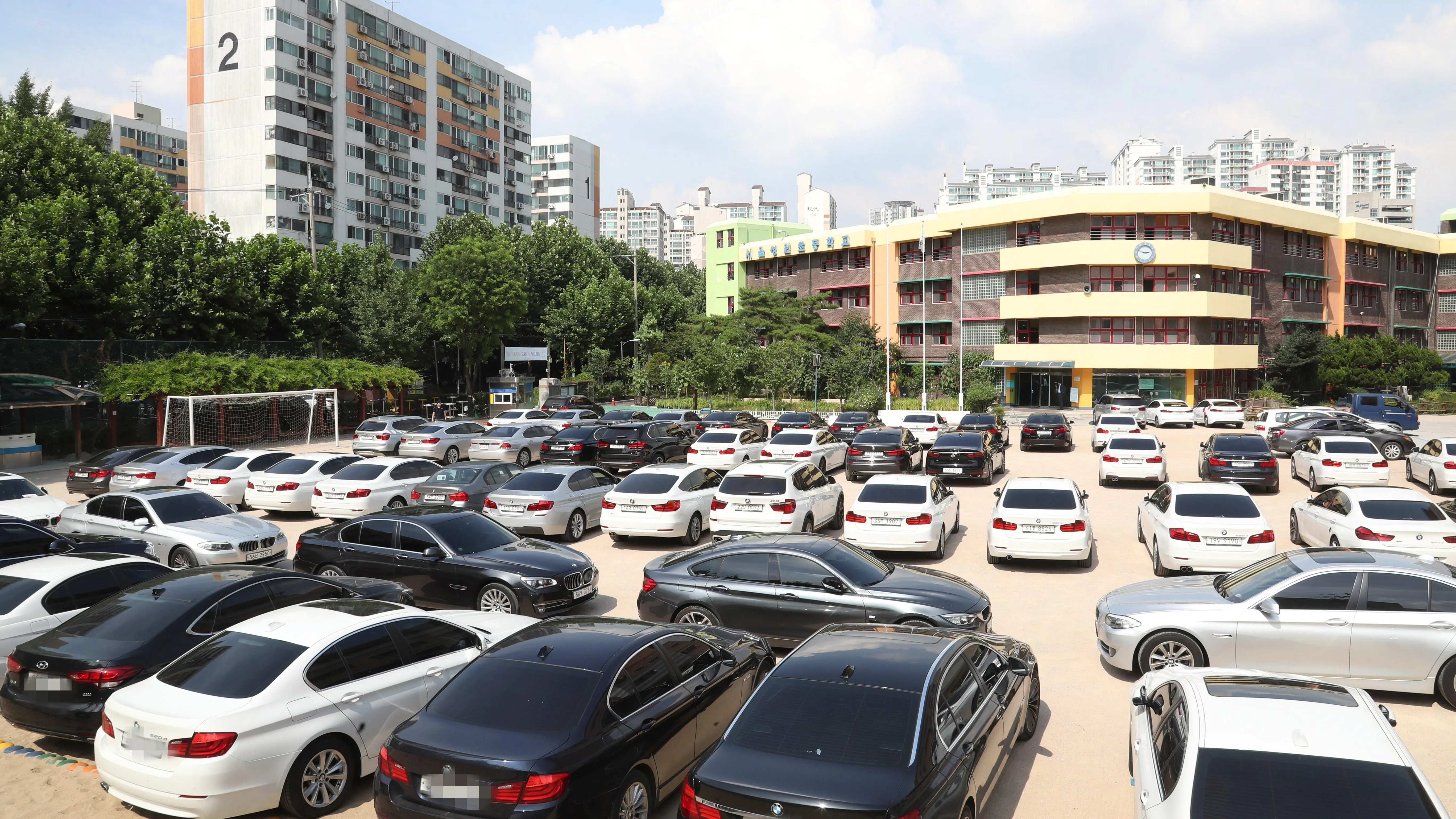 Vista de decenas de vehículos BMW permanecen aparcados en el patio de un colegio en Seúl