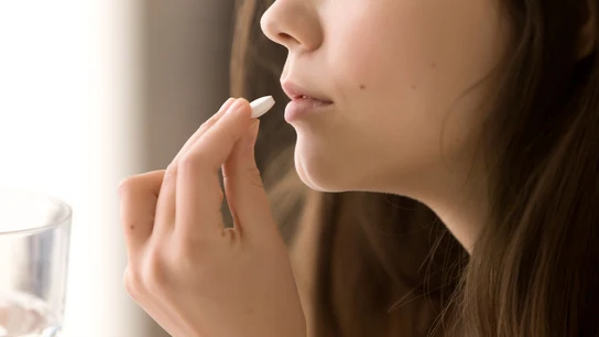 Imagen de una mujer tomando una pastilla. Imagen de una mujer tomando una pastilla.