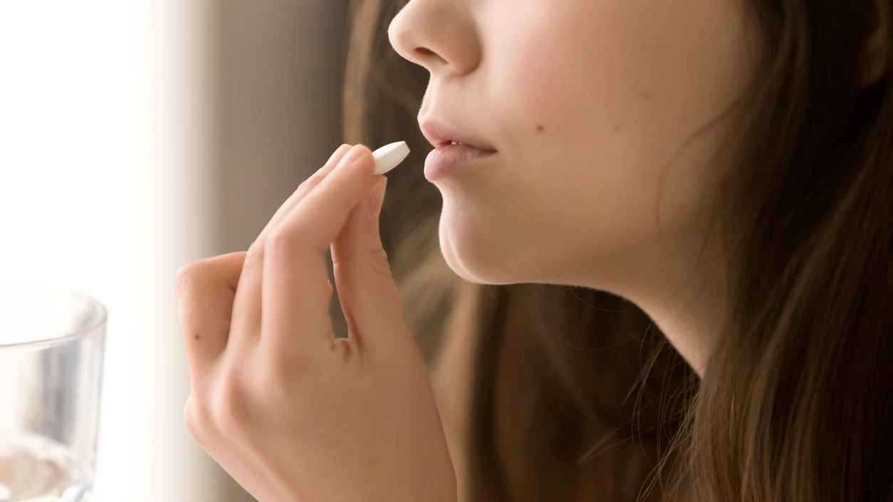 Imagen de una mujer tomando una pastilla.