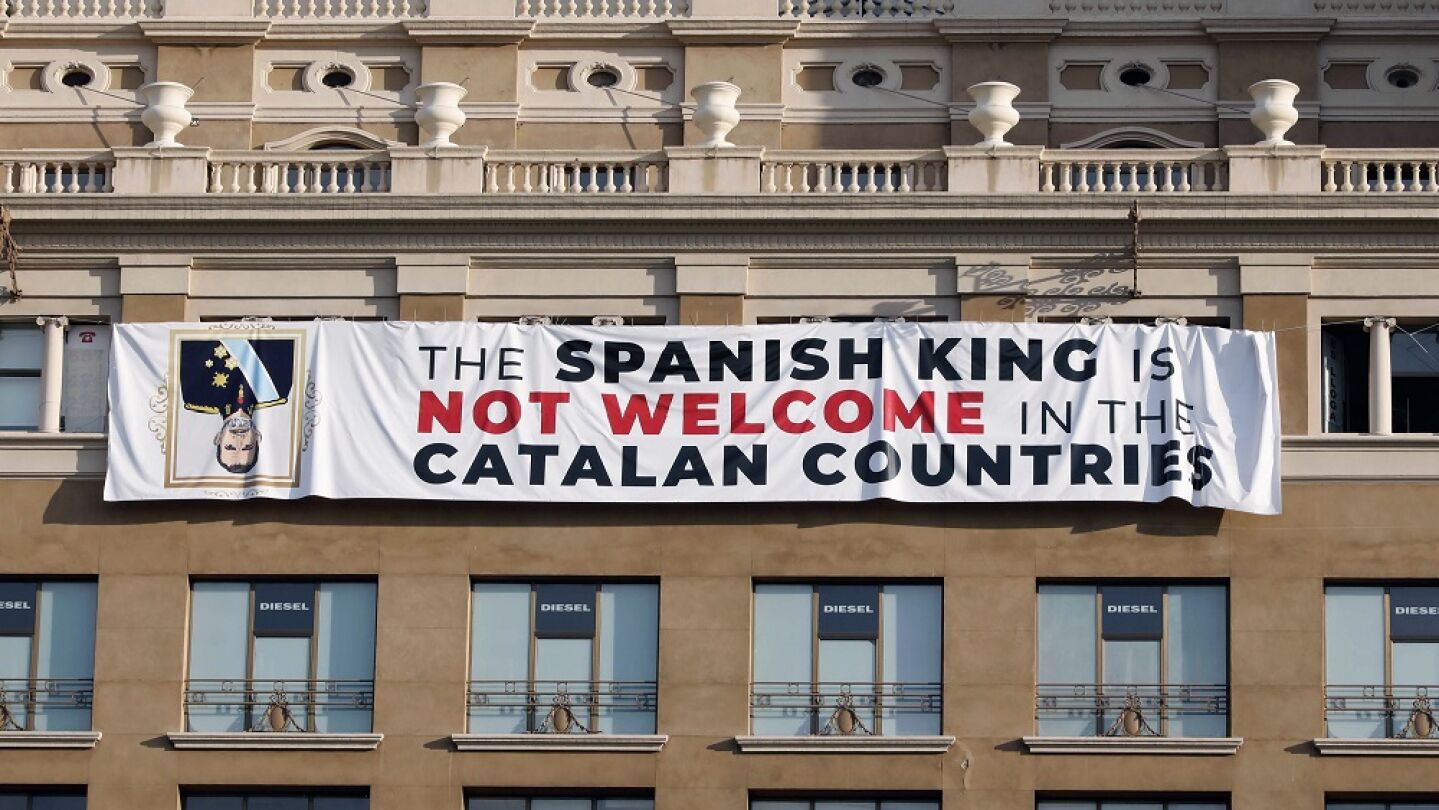 pancarta en contra del rey en la fachada de un edificio de la plaza de Catalu&ntilde;a de Barcelona, donde se va a celebrar el acto central en recuerdo de las v&iacute;ctimas de los atentados del 17A