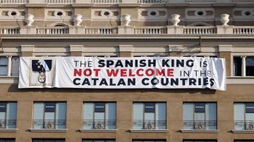 pancarta en contra del rey en la fachada de un edificio de la plaza de Cataluña de Barcelona, donde se va a celebrar el acto central en recuerdo de las víctimas de los atentados del 17A