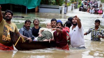 Un grupo de hombres evacua a un anciano en una barca durante las inundaciones sufridas en India