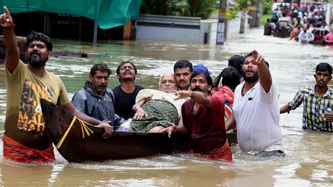 Un grupo de hombres evacua a un anciano en una barca durante las inundaciones sufridas en India