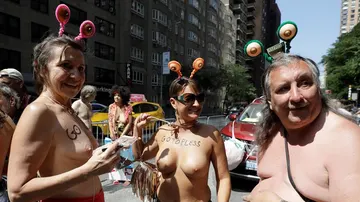 En la imagen tres manifestantes, entre ellos, un hombre, en el 'Día del Topless' en Nueva York