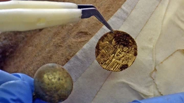Un arquéologo limpia una moneda de oro del tesoro descubierto en la fortaleza de Kaliakra