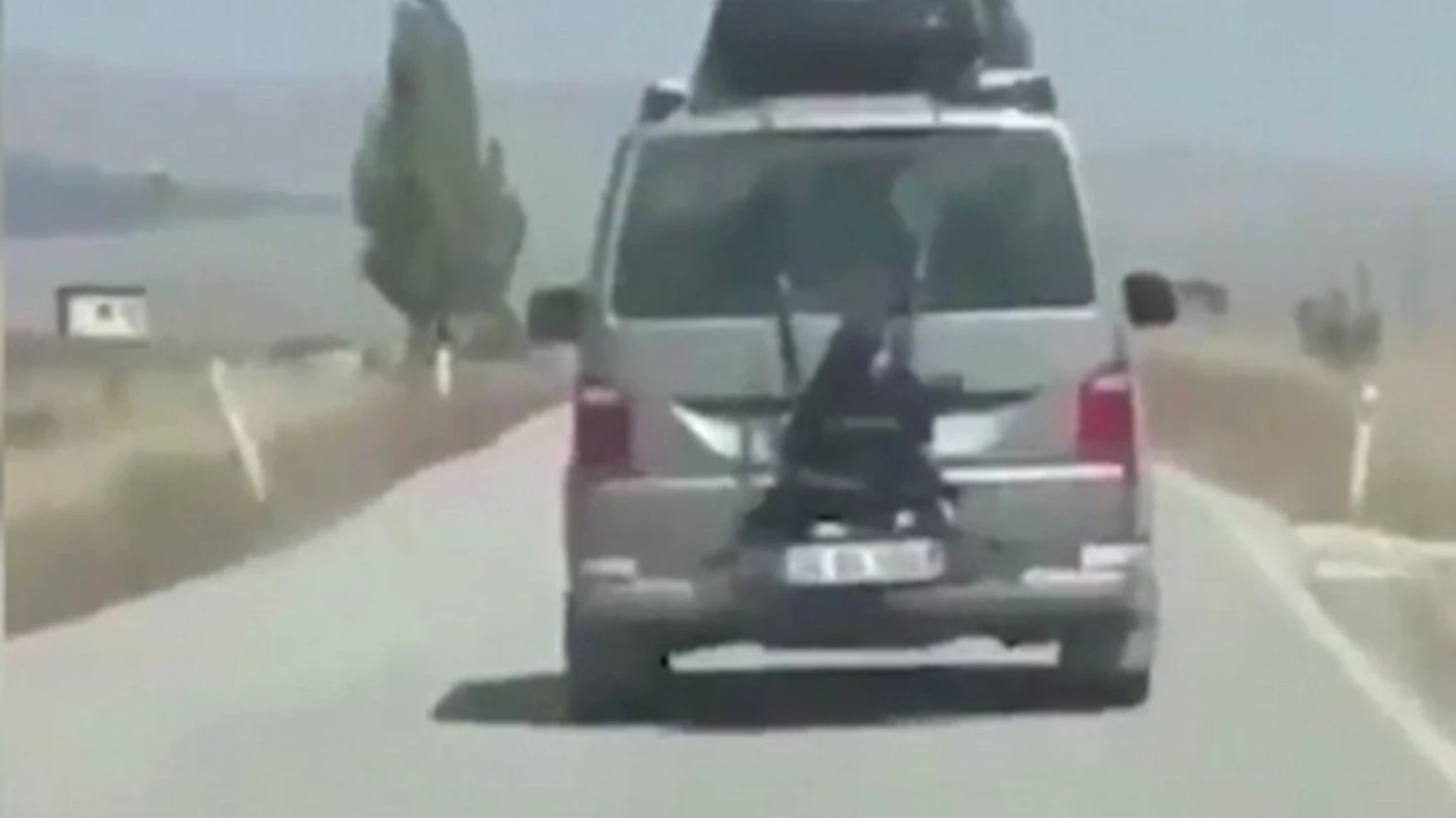 Niña atada a la parte trasera de un coche Niña atada a la parte trasera de un coche