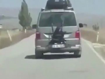 Niña atada a la parte trasera de un coche Niña atada a la parte trasera de un coche