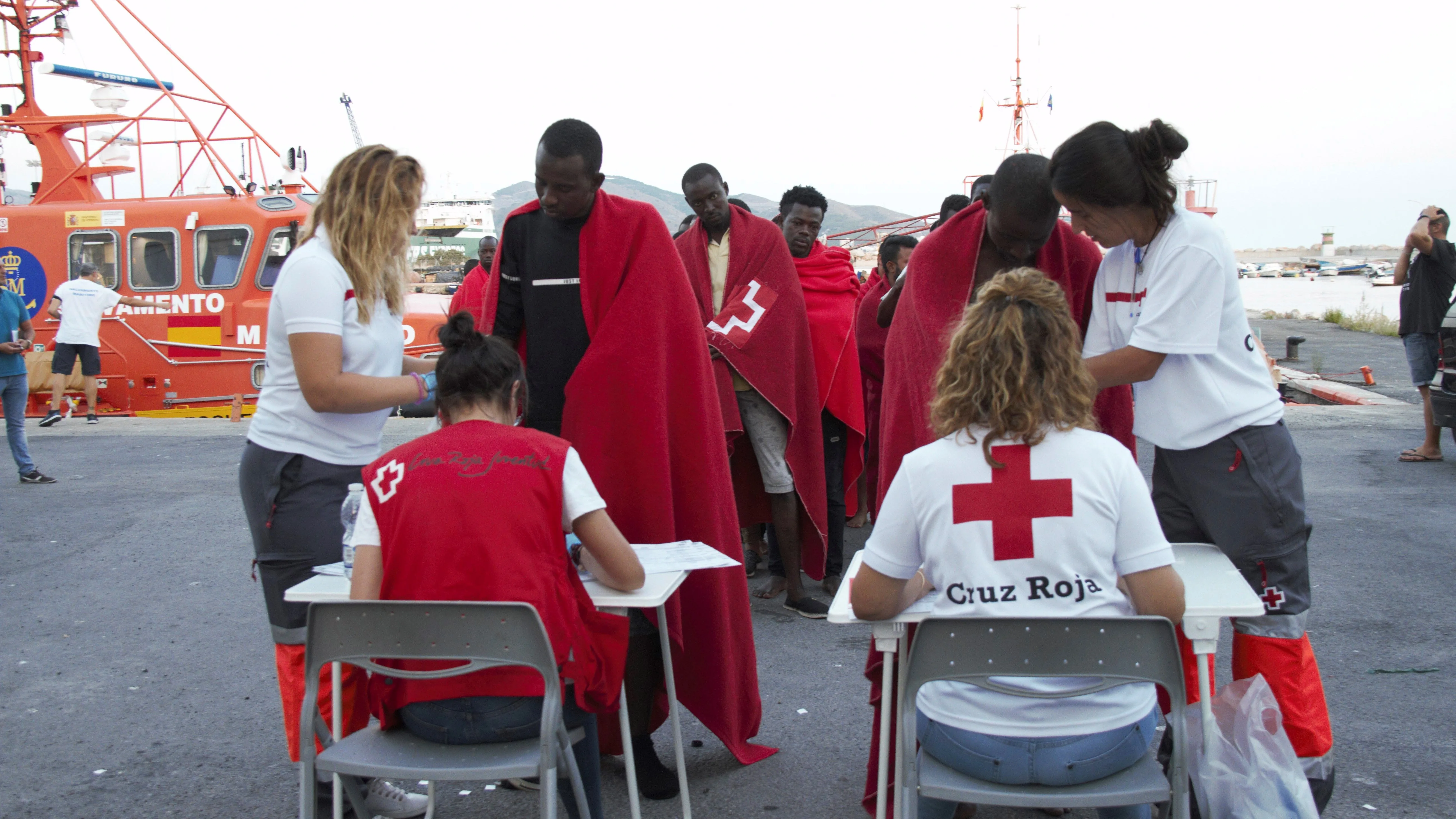 Miembros de la Cruz Roja atienden a decenas de migrantes rescatados por Salvamento Marítimo de una patera en la cercanías de la Isla de Alborán