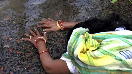 Una devota india reza recostada en el río Ganges Una devota india reza recostada en el río Ganges