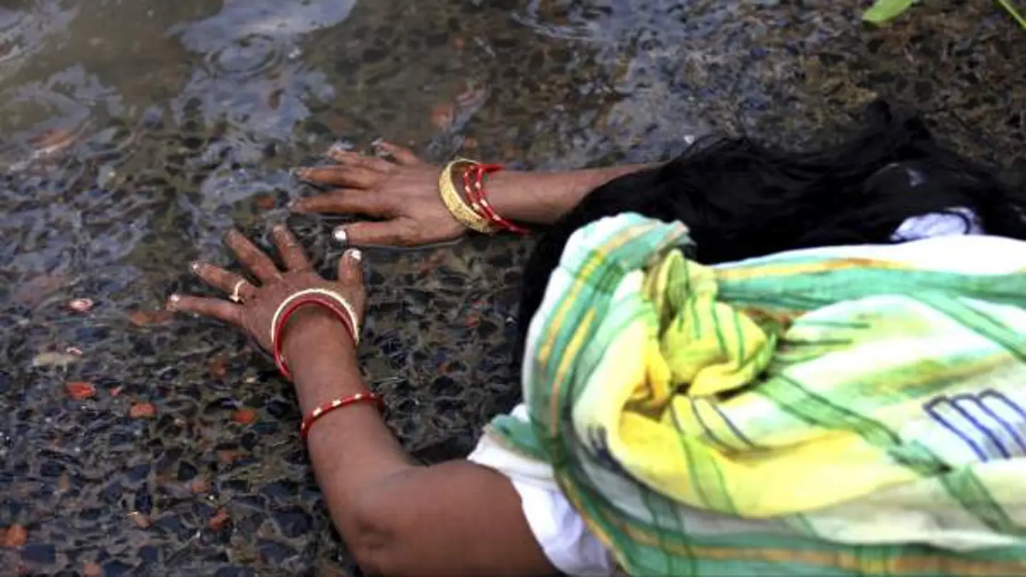 Una devota india reza recostada en el río Ganges Una devota india reza recostada en el río Ganges