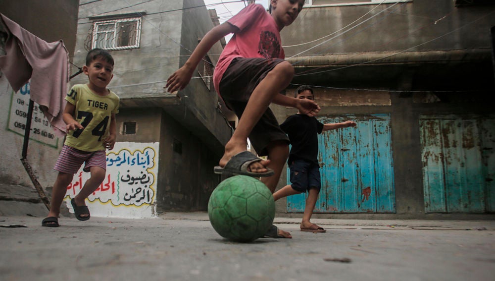 Niños palestinos jugando fútbol en un campo de refugiados