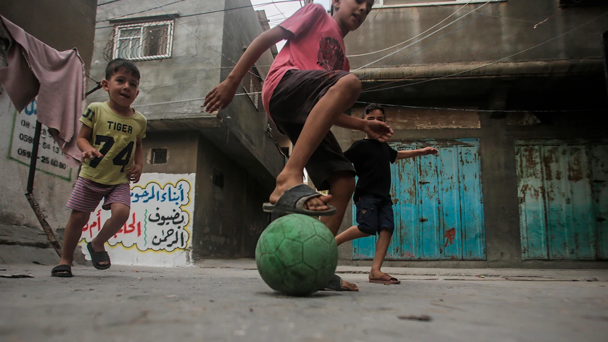 Niños palestinos jugando fútbol en un campo de refugiados