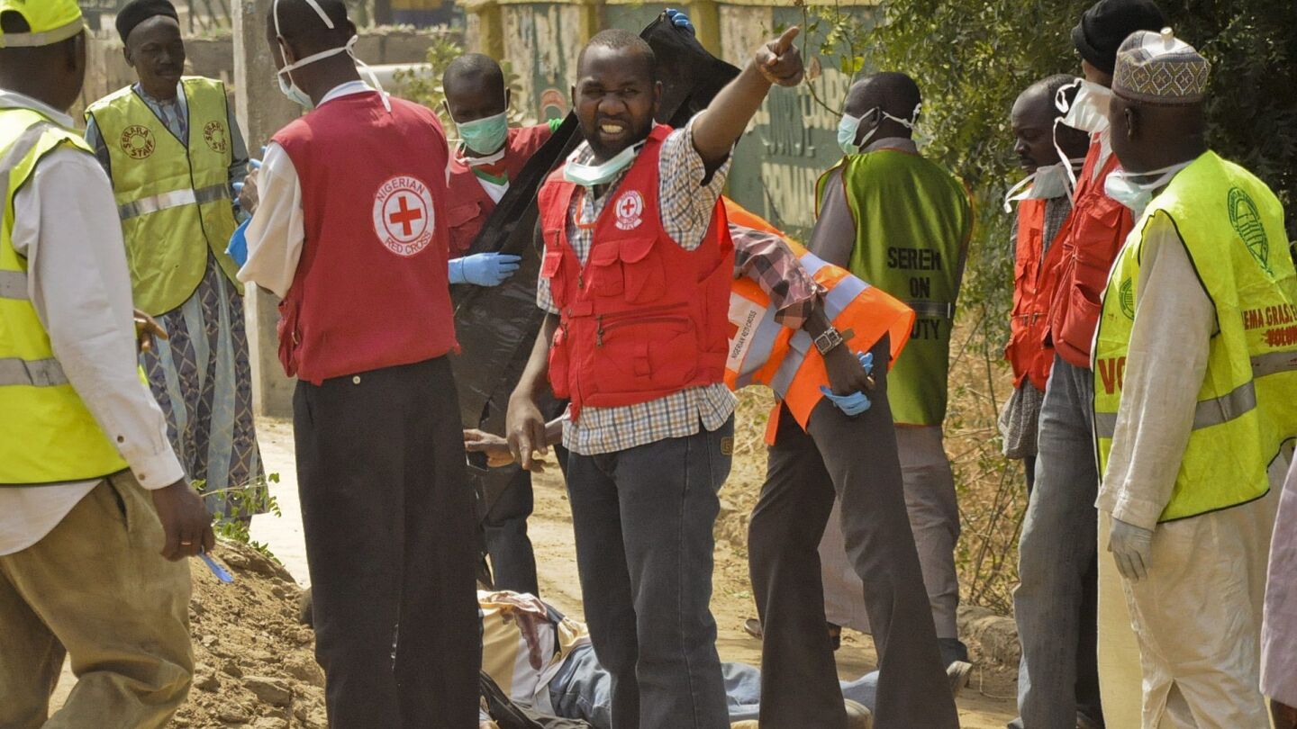 Miembros de la Cruz Roja y de la Agencia Nacional de Emergencias de Nigeria (NEMA), trasladando el cuerpo de una v&iacute;ctima, en la ciudad septentrional nigeriana de Kano